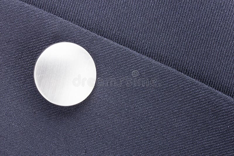 Close-up photograph of a silver button on gray material.