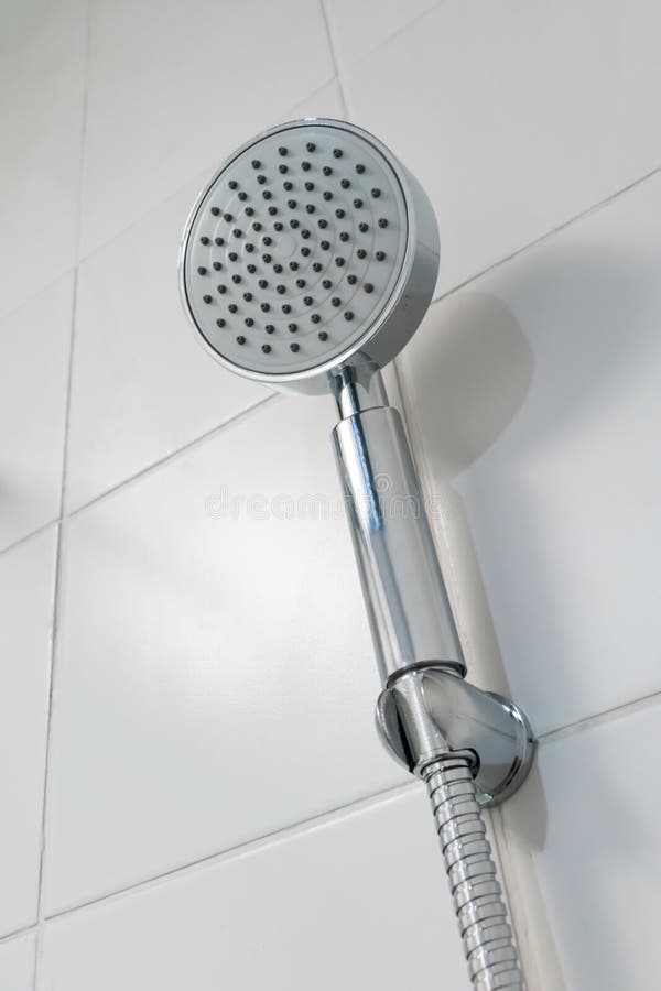 Silver Circle Shower Head Hanging Against White Ceramic Tile Wall Stock