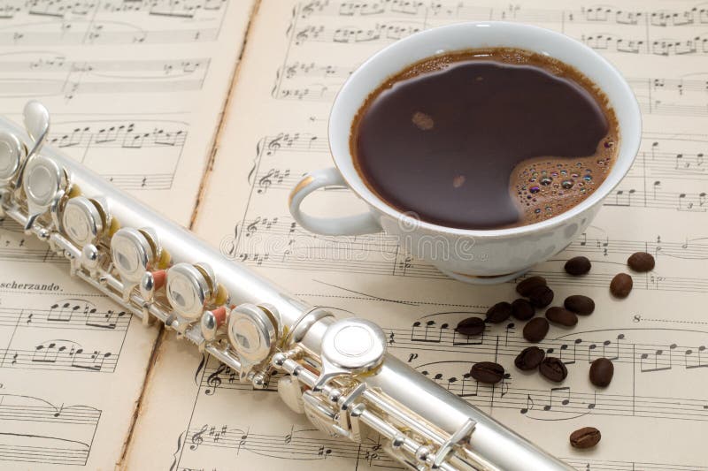 Silver Flute, Cup of Coffee and Coffee Beans on an Ancient Music Score