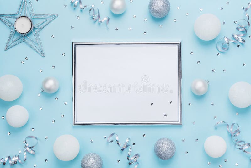 Silver frame and christmas decoration on stylish blue table top view. Fashion background. Flat lay. Party mockup, invitation or greeting card.