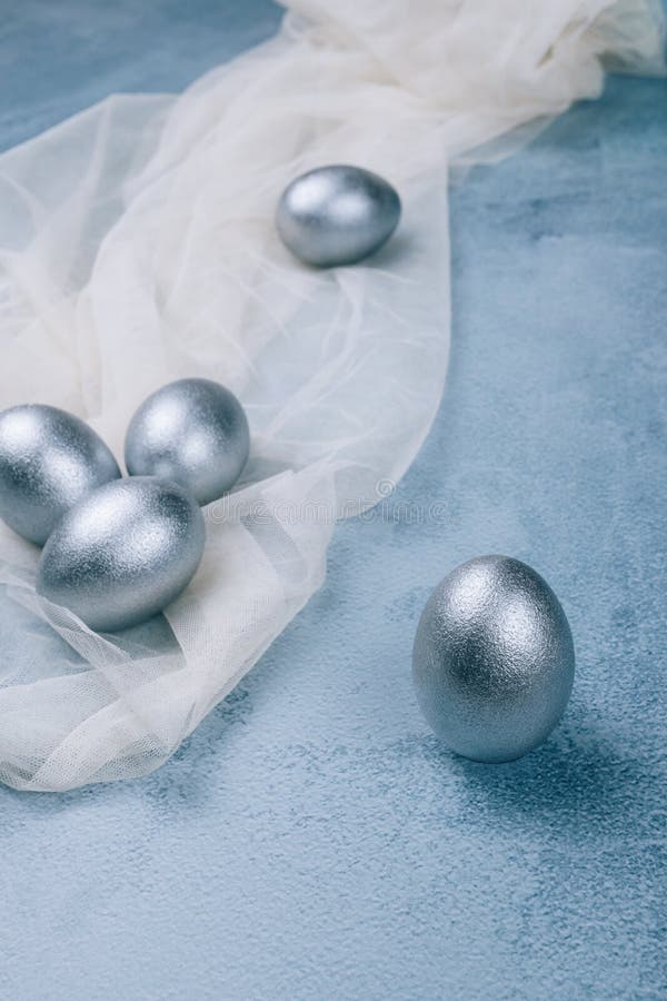 Silver Grey Painted Easter Eggs on White Napkin on Textured Blue