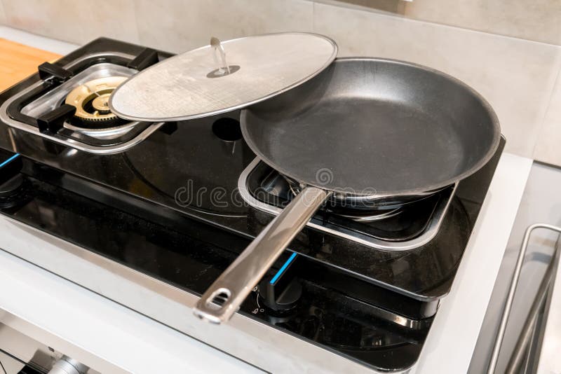 Silvermetallstekpannan som täckas med olja, plaskar skärmen royaltyfri bild Silvermetallstekpannan som täckas med olja, plaskar skärmen royaltyfri bild