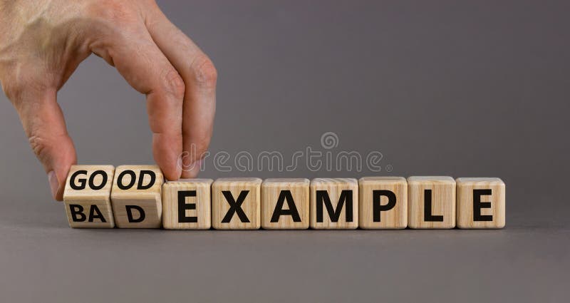 Simbol bun sau negativ. om de afaceri transformă cuburi de lemn și schimbă cuvintele ca pe un exemplu bun. gri frumos royalty free stock photos