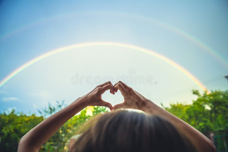 Simbolismo de amor, cielo arco iris, amor. manos con forma de corazón y arco iris en el cielo. arco iris doble imagen de archivo libre de regalías Simbolismo de amor, cielo arco iris, amor. manos con forma de corazón y arco iris en el cielo. arco iris doble imagen de archivo libre de regalías