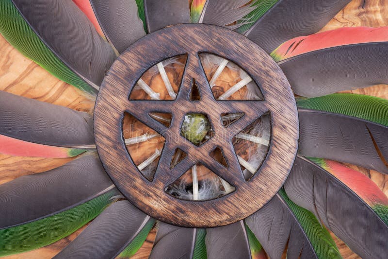 Simbolo circondato di legno del pentagramma con la pietra di Unakite in mezzo ad un cerchio fatto delle piume variopinte del papp immagine stock libera da diritti Simbolo circondato di legno del pentagramma con la pietra di Unakite in mezzo ad un cerchio fatto delle piume variopinte del papp immagine stock libera da diritti