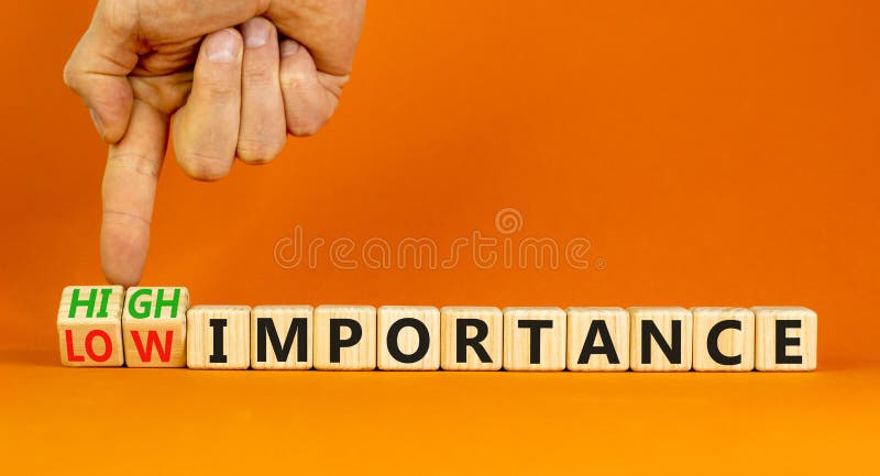 High or low importance symbol. Concept words High importance and Low importance on wooden cubes. Businessman hand. Beautiful orange background. Business high or low importance concept. Copy space. High or low importance symbol. Concept words High importance and Low importance on wooden cubes. Businessman hand. Beautiful orange background. Business high or low importance concept. Copy space