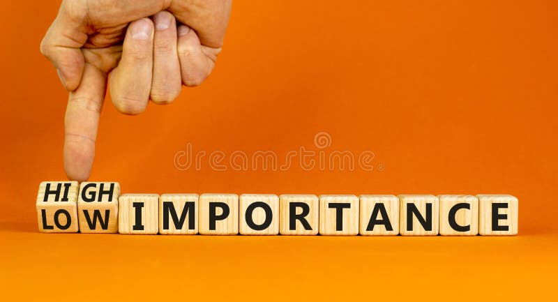High or low importance symbol. Concept words High importance and Low importance on wooden cubes. Businessman hand. Beautiful orange background. Business high or low importance concept. Copy space. High or low importance symbol. Concept words High importance and Low importance on wooden cubes. Businessman hand. Beautiful orange background. Business high or low importance concept. Copy space