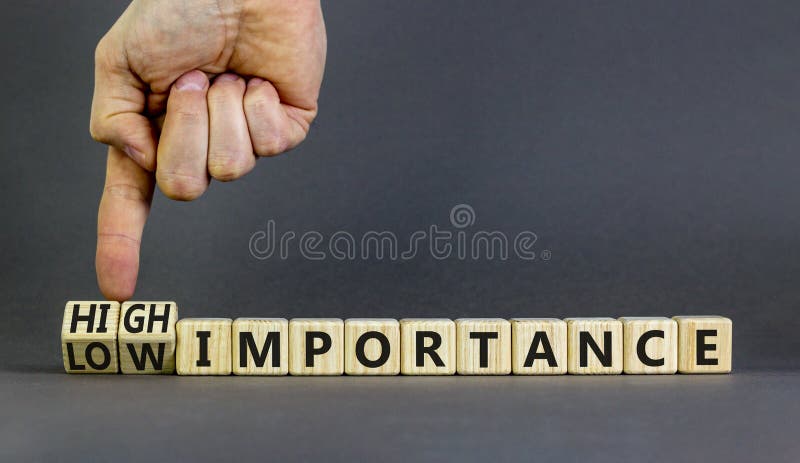 High or low importance symbol. Concept words High importance and Low importance on wooden cubes. Businessman hand. Beautiful grey background. Business high or low importance concept. Copy space. High or low importance symbol. Concept words High importance and Low importance on wooden cubes. Businessman hand. Beautiful grey background. Business high or low importance concept. Copy space