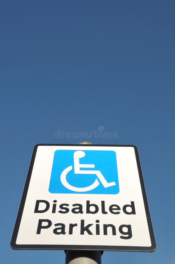 Low angle view of Disabled Parking sign with wheelchair mobility symbol, set against a clear blue sky with space for type. Low angle view of Disabled Parking sign with wheelchair mobility symbol, set against a clear blue sky with space for type.