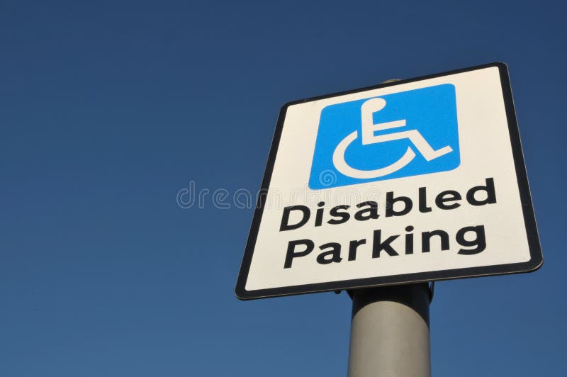 Low angle view of Disabled Parking sign with wheelchair mobility symbol, set against a clear blue sky with space for type. Low angle view of Disabled Parking sign with wheelchair mobility symbol, set against a clear blue sky with space for type.