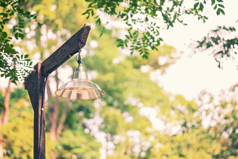 Simple basic lamp on old rustic wooden lampost against blurred t