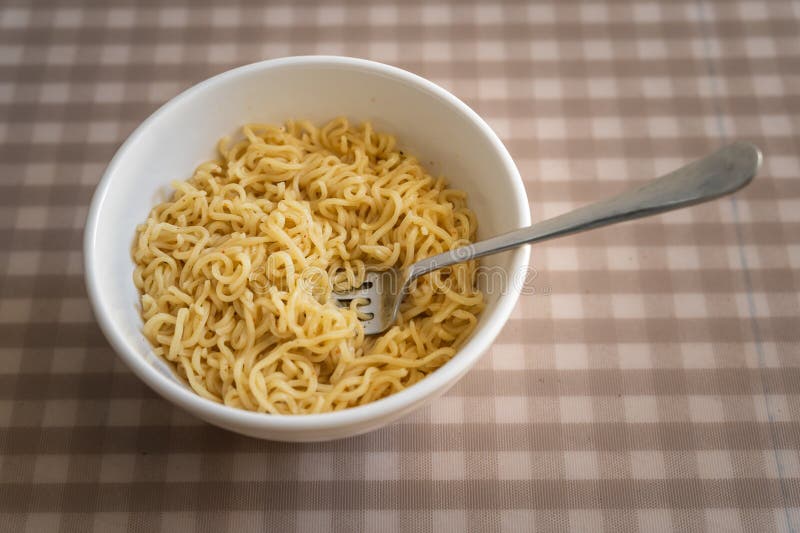 Simple cooked instant noodles on a checkered tablecloth royalty free stock image
