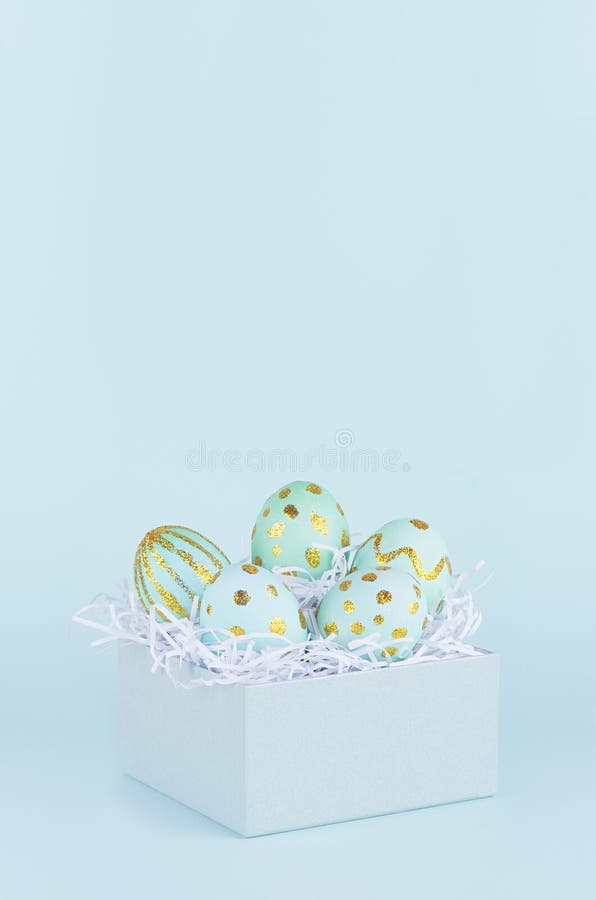 Simple and minimal easter background - easter eggs with golden design in gift box on blue color, vertical. stock photos