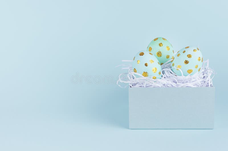 Simple and minimal easter background - easter eggs with golden dots in gift box on blue backdrop. stock image