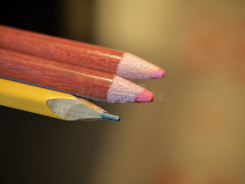 A Simple Pencil and Two Colored Ones on a Blurry Background Stock Photo
