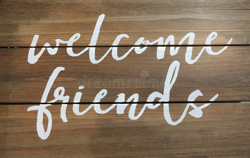 White welcome friends sign print on wood wall. White welcome friends sign print on wood wall.