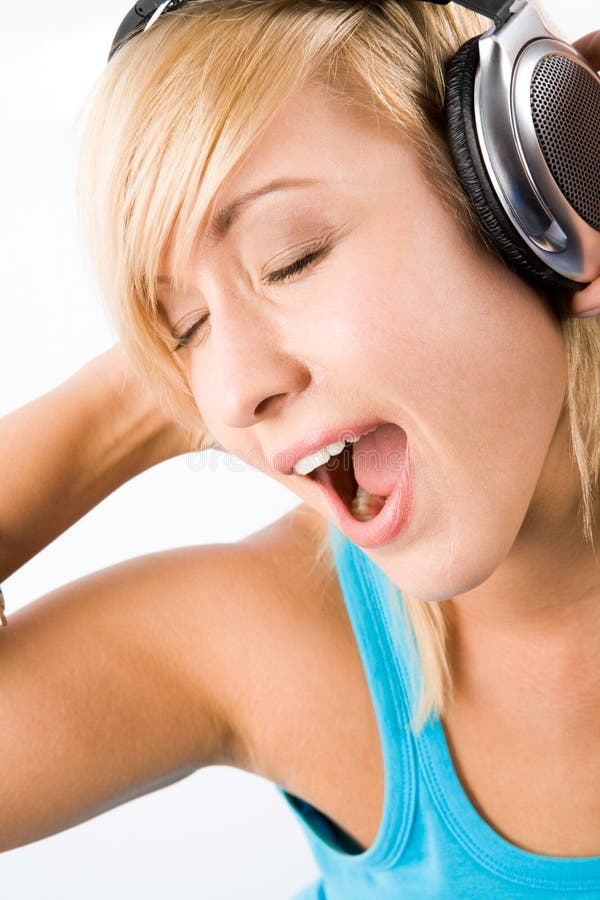 Image of modern teenage girl wearing headphones with her mouth wide open while singing