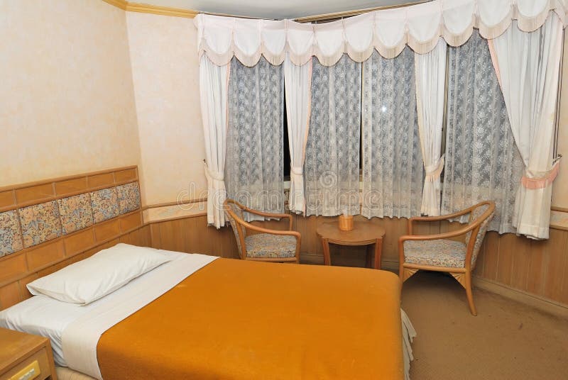 Single bed in modern hotel room with furniture