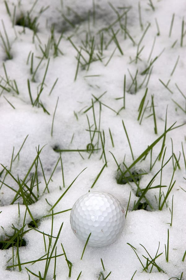 Single dimpled golf ball in the snow covered grass