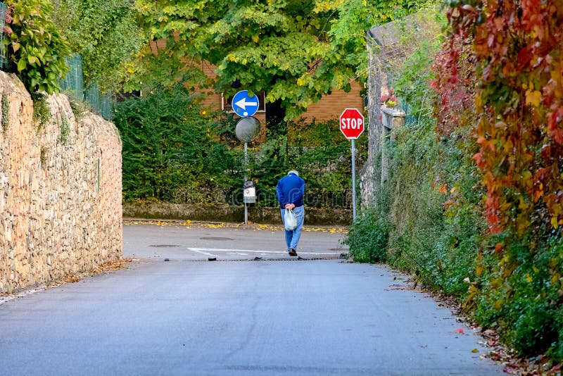 Single hunched old man walking down the street. Social problems of old age, poverty