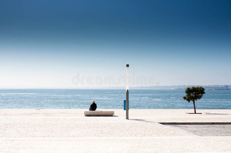 Single man sitting on a bench and looking at the sea. Lonely sad