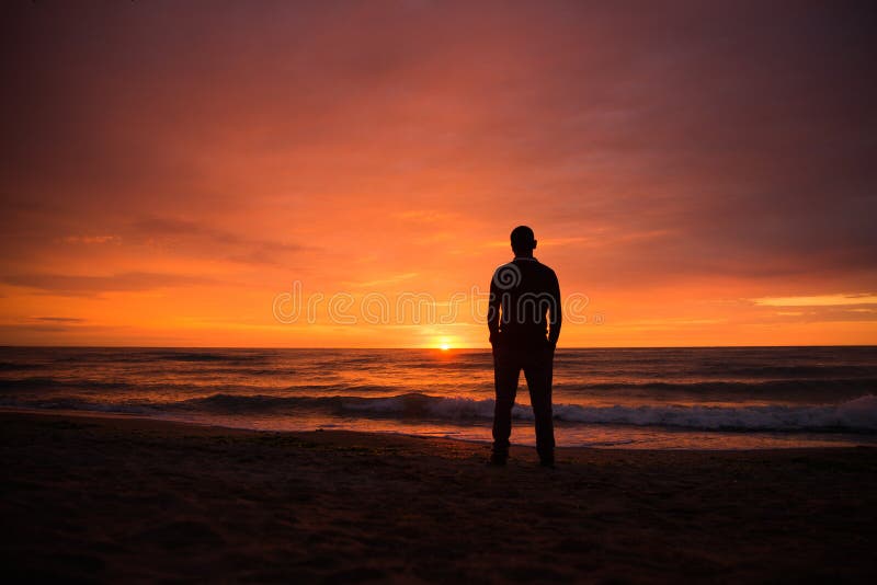 Single man watching a dramatic sunset by the sea