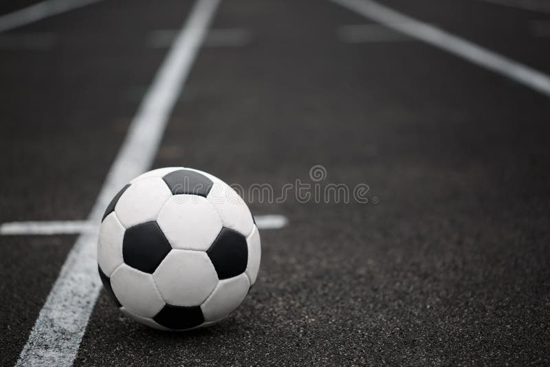 A classic football ball on an asphalted path background. Children training soccer. Healthy lifestyle. A ball on a grass.