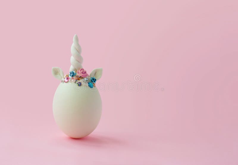 Single white egg, with unicorn decoration; Creative minimal Easter background with copy space stock photography