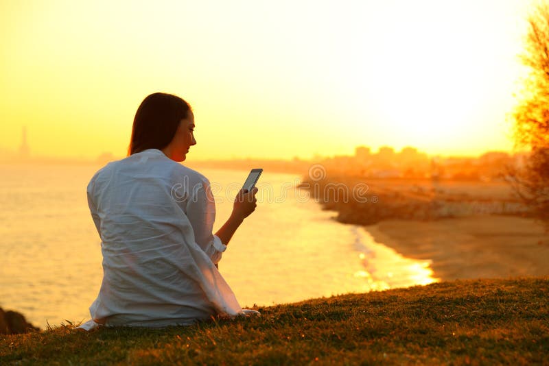 Single woman using a smart phone at sunset stock image Single woman using a smart phone at sunset stock image