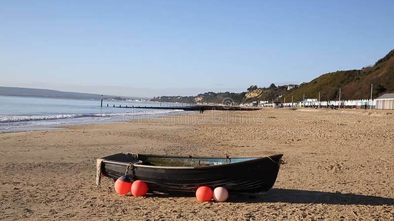 Single wooden rowing boat on sandy beach in the UK with buoys and flotation aids