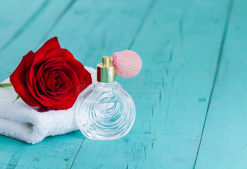 Singola bottiglia di profumo e della rosa rossa sul fondo di legno blu dell'alzavola immagine stock Singola bottiglia di profumo e della rosa rossa sul fondo di legno blu dell'alzavola immagine stock