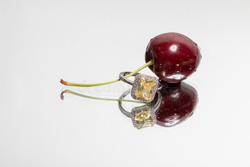 Singoli ciliegia ed anello con la riflessione su un fondo leggero immagine stock Singoli ciliegia ed anello con la riflessione su un fondo leggero immagine stock
