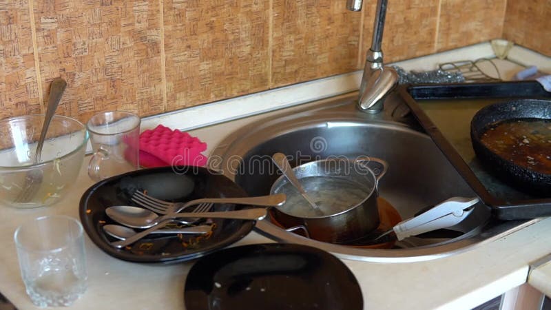 Sink full of dirty dishes and utencil mess. Neglected pile of bowls, plates, spoons and forks