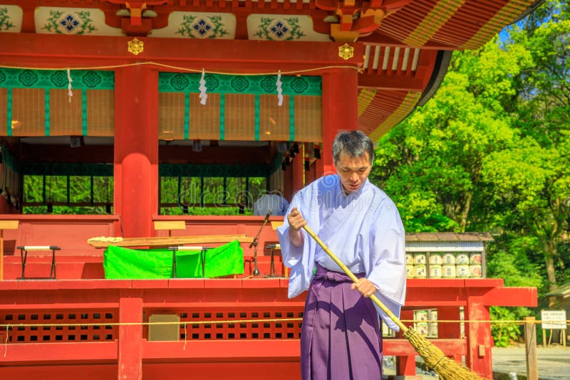 Kamakura, Japan - April 23, 2017: close-up of Shinto priest who cleans inside Tsurugaoka Hachiman Shinto shrine in the city of Kamakura, Kanagawa Prefecture. Kamakura, Japan - April 23, 2017: close-up of Shinto priest who cleans inside Tsurugaoka Hachiman Shinto shrine in the city of Kamakura, Kanagawa Prefecture.