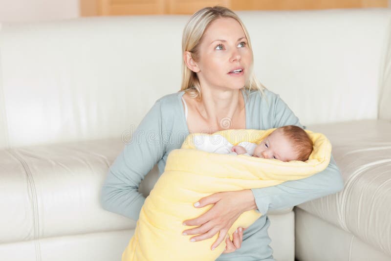 Sira de mãe ao assento com seu bebê na frente do sofá imagens de stock royalty free Sira de mãe ao assento com seu bebê na frente do sofá imagens de stock royalty free