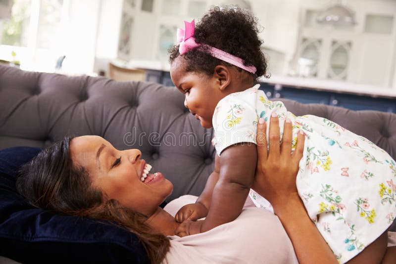 Sira de mãe ao encontro retendo sua filha da criança sobre ela fotografia de stock Sira de mãe ao encontro retendo sua filha da criança sobre ela fotografia de stock