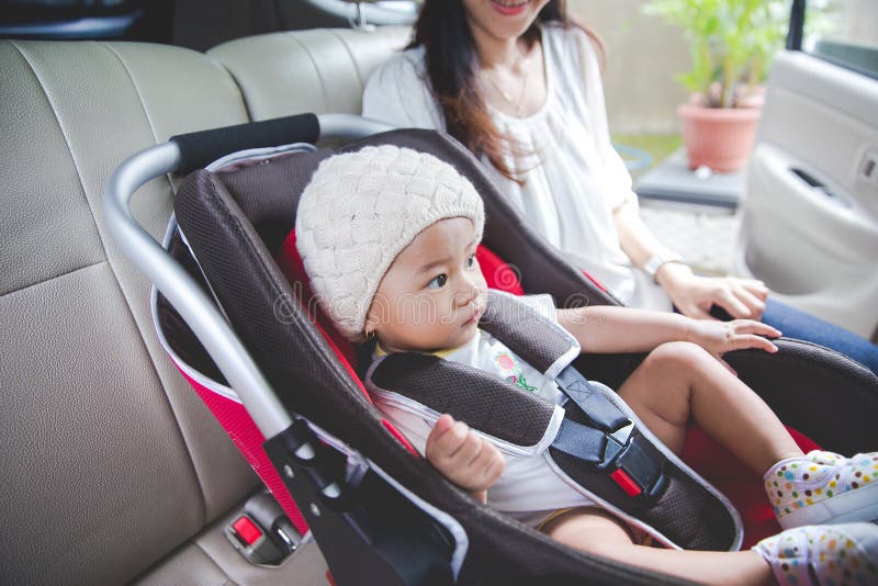Sira de mãe a fixar seu bebê no banco de carro em seu carro fotografia de stock Sira de mãe a fixar seu bebê no banco de carro em seu carro fotografia de stock