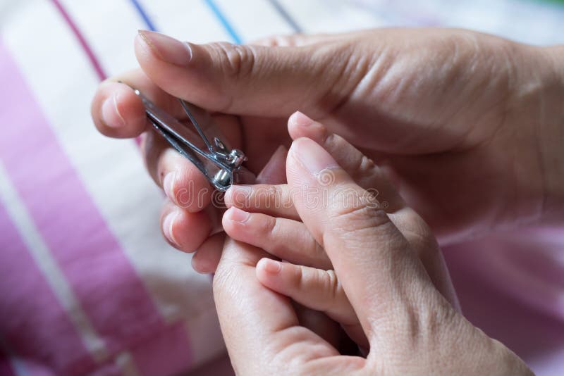 Sira de mãe a pregos de corte com as tesouras ao bebê foto de stock Sira de mãe a pregos de corte com as tesouras ao bebê foto de stock