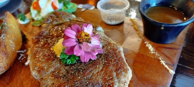 Sirloin Beef Steak on Wooden Plate Serve with Pepper Sauce and Flower