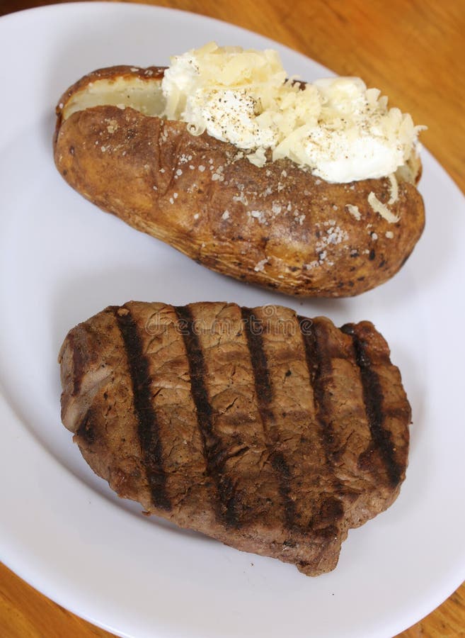 Sirloin Steak with Baked Potato and Fresh Rolls in Background Shallow