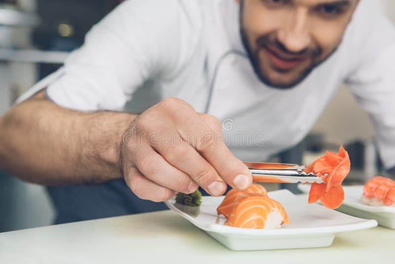 Sirva al cocinero del restaurante japonés que cocina en la cocina imagen de archivo libre de regalías Sirva al cocinero del restaurante japonés que cocina en la cocina imagen de archivo libre de regalías