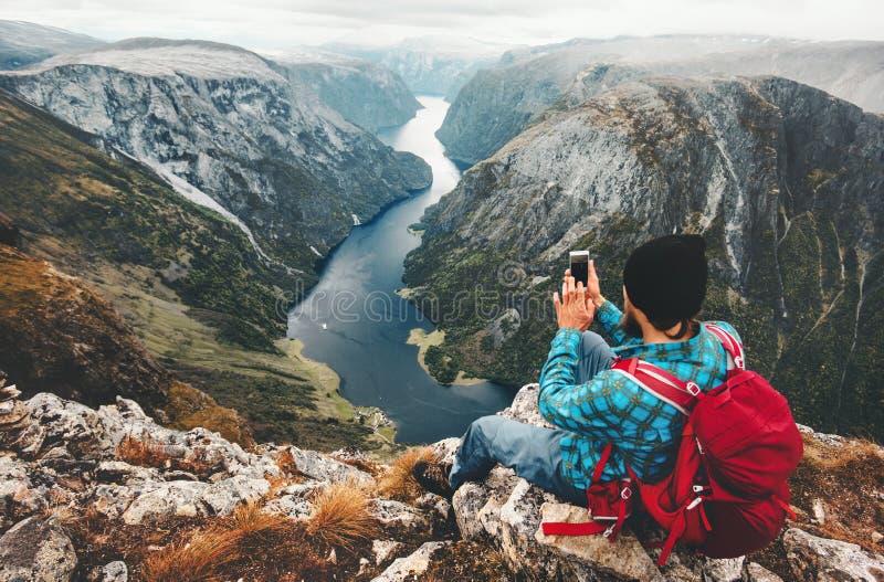 Sirva al viajero que usa el smartphone que se sienta en cumbre de la montaña foto de archivo Sirva al viajero que usa el smartphone que se sienta en cumbre de la montaña foto de archivo