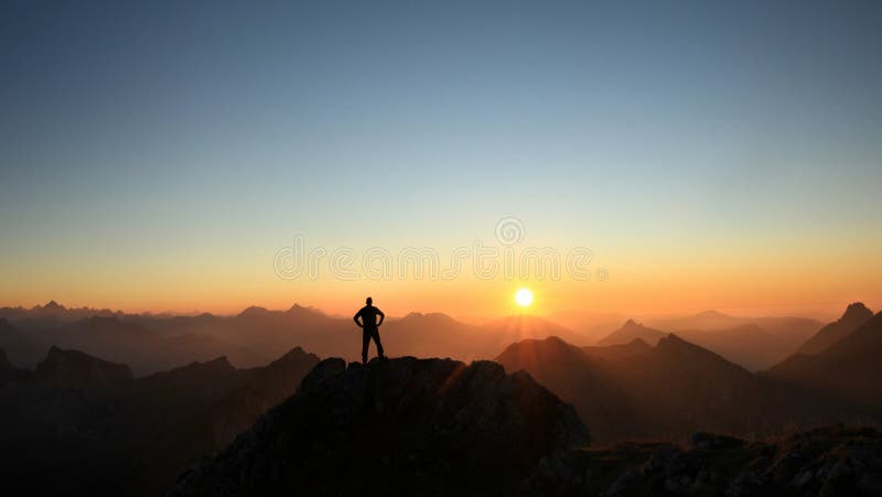 Sirva alcanzar la cumbre que disfruta de la libertad y que mira hacia puesta del sol de las montañas imagen de archivo Sirva alcanzar la cumbre que disfruta de la libertad y que mira hacia puesta del sol de las montañas imagen de archivo
