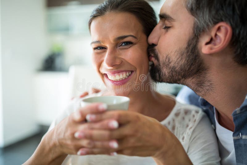 Man kissing women on cheeks while having coffee at home. Man kissing women on cheeks while having coffee at home
