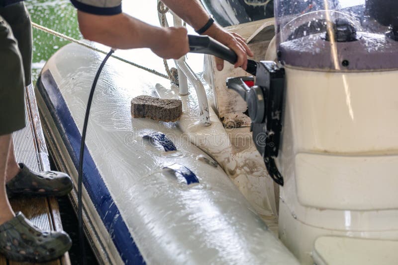 Sirva el barco inflable blanco que se lava con el cepillo y el circuito de agua de la presión en el garaje Servicio de la nave y imagen de archivo libre de regalías Sirva el barco inflable blanco que se lava con el cepillo y el circuito de agua de la presión en el garaje Servicio de la nave y imagen de archivo libre de regalías