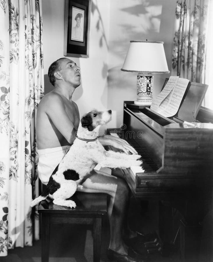 Man playing a piano with his dog next to him (All persons depicted are no longer living and no estate exists. Supplier grants that there will be no model release issues.). Man playing a piano with his dog next to him (All persons depicted are no longer living and no estate exists. Supplier grants that there will be no model release issues.)