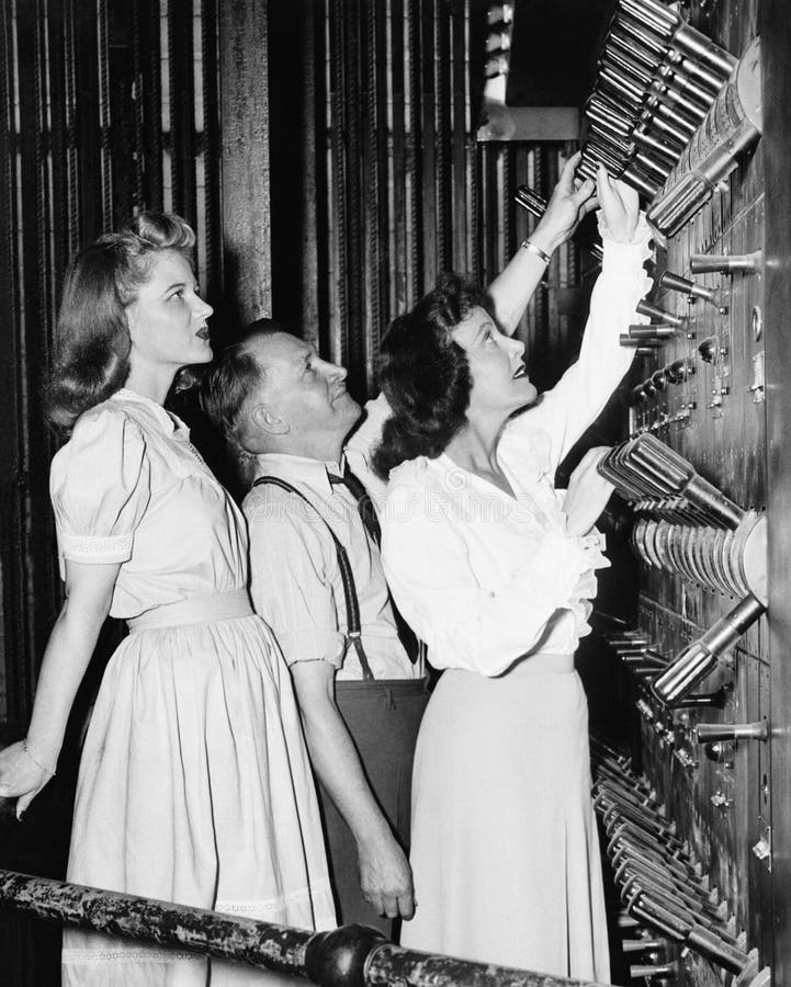 Man showing women control levers in theater (All persons depicted are no longer living and no estate exists. Supplier grants that there will be no model release issues.). Man showing women control levers in theater (All persons depicted are no longer living and no estate exists. Supplier grants that there will be no model release issues.)