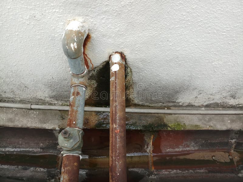 Sistema de tuberías de acero desgastado con una pared blanca y una zanja en la parte inferior El foso está sucio Cerrar fotos de archivo libres de regalías Sistema de tuberías de acero desgastado con una pared blanca y una zanja en la parte inferior El foso está sucio Cerrar fotos de archivo libres de regalías
