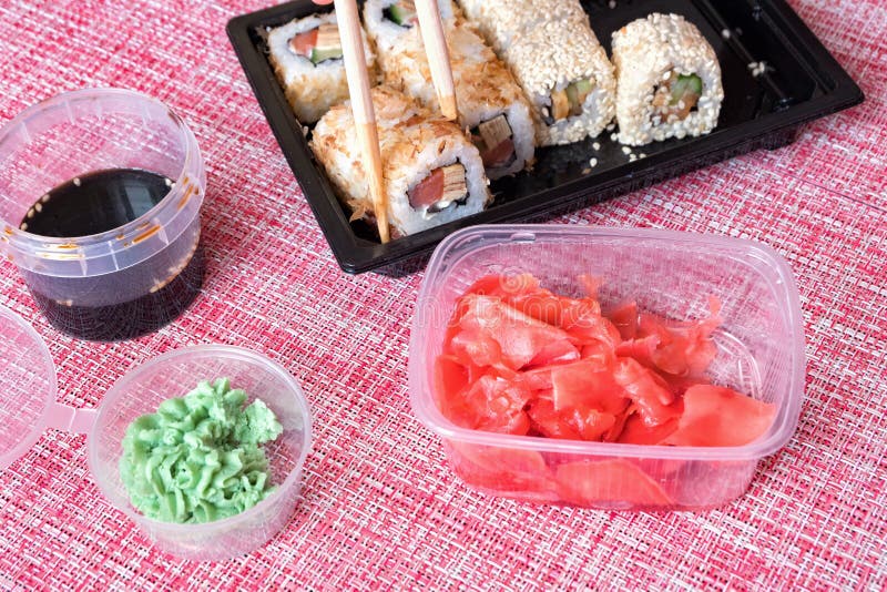 Sistema del rollo de sushi, salsa de soja, wasabi, jengibre conservado en vinagre, palillos en un envase disponible en una servil imagenes de archivo Sistema del rollo de sushi, salsa de soja, wasabi, jengibre conservado en vinagre, palillos en un envase disponible en una servil imagenes de archivo