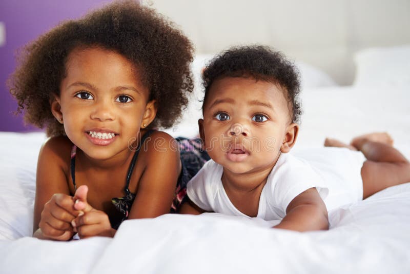 Sister With Baby Brother Lying On Parent's Bed royalty free stock photos